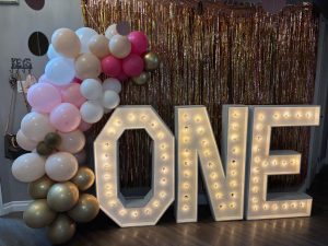 Marquee letters that spell out "ONE" framed with balloon decor