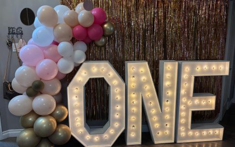 Marquee letters that spell out "ONE" framed with balloon decor