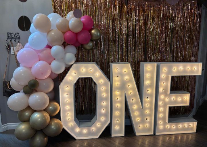 Marquee letters that spell out "ONE" framed with balloon decor