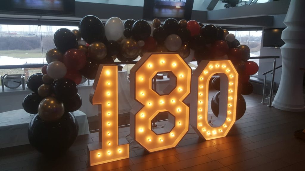 Marquee numbers in Bolton that spel lout 180, with a balloon arch