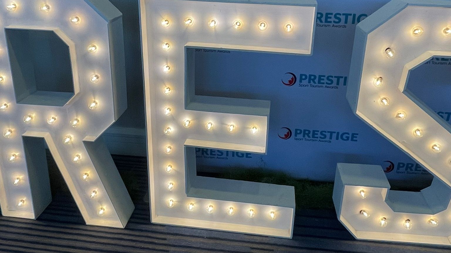 The letters RES lit in front of an awards step and repeat backdrop